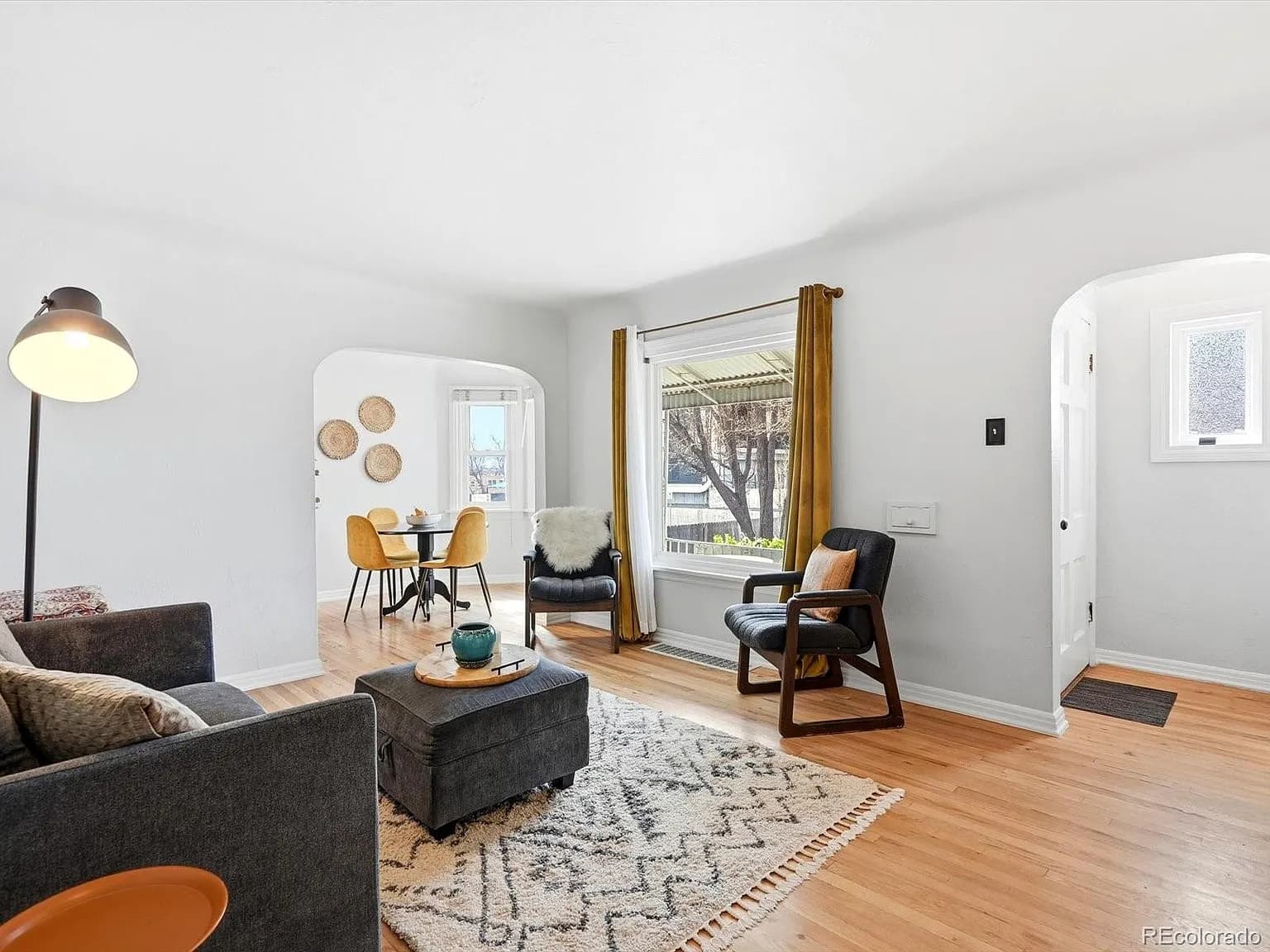 Living room with original hardwood floors, charming archways, and dining area